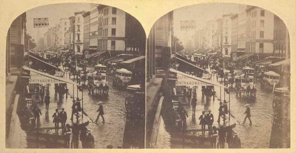 Gammal stadsvy med trådbussar och människor på gatan.
