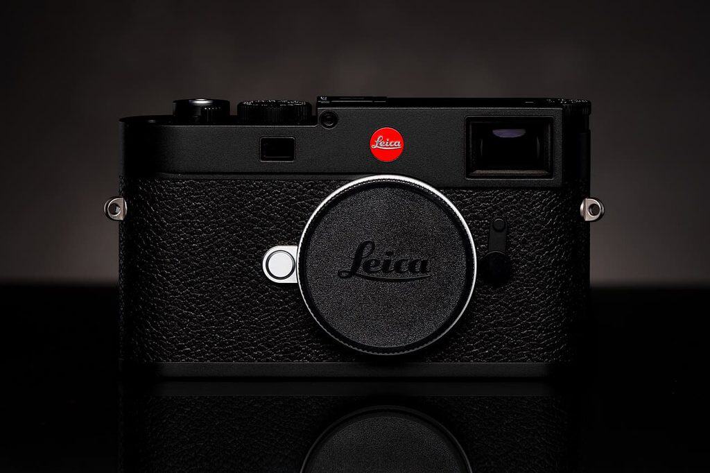 Svart Leica M11 rakt framifrån med den röda punkten synlig ovanför objektivfattningen