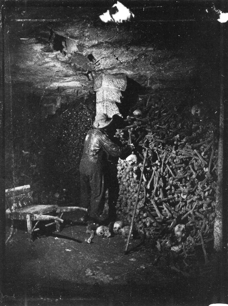 Gammal svartvit bild av en man som arbetar med ett eldfat i ett mörkt rum.