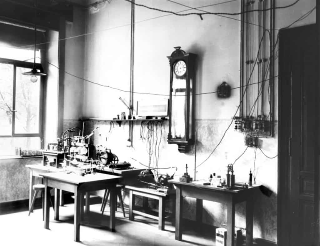 Ett högt laboratorierum med långa arbetsbänkar, glasskåp längs väggarna och instrument uppradade på borden.