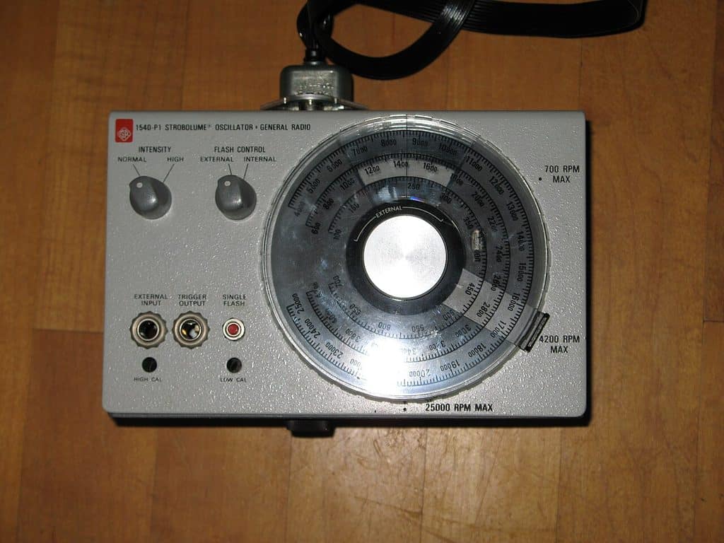 Grå instrumentlåda fotograferad rakt ovanifrån mot ett trägolv. På fronten står texten 1540-P1 Strobolume Oscillator, General Radio. Till vänster två vridreglage märkta Intensity och Flash Control samt tre anslutningar, till höger en stor rund skala med flera koncentriska sifferringar och en vridratt i mitten.