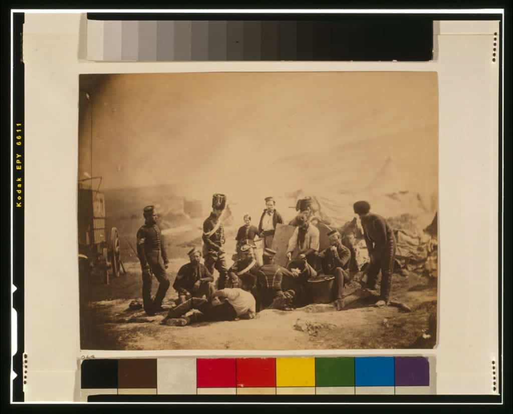 Militärmän samlade vid ett fält under krigstid, sepia-tonad fotografi.