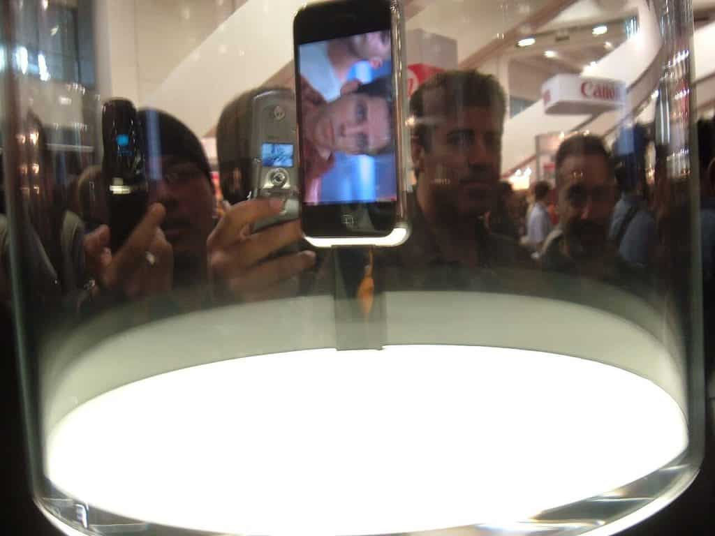 Den första iPhone utställd under en glaskupa på Macworld, med startskärmens ikoner tända.