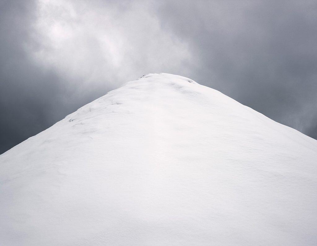 Snötäckt hög av makadam som reser sig som en fjälltopp mot mörka moln