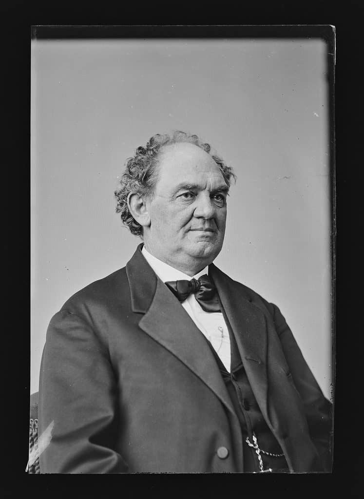 Svartvitt porträtt av P.T. Barnum i halvfigur, en kraftig man med lockigt hår och mörk rock.