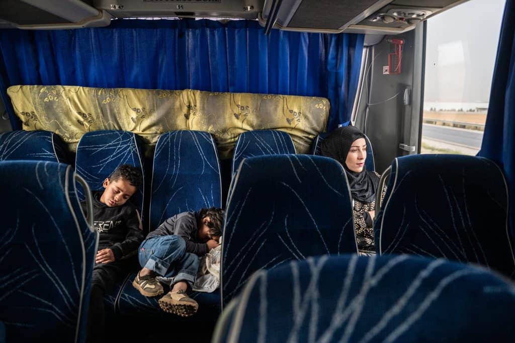 Zeinab tittar ut genom bussfönstret medan två av hennes barn sover på sätena bredvid